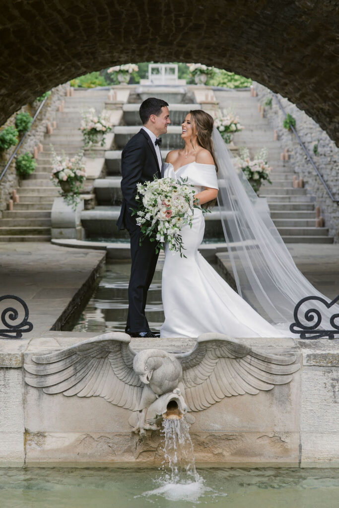 newly married couple poses behind a fountain