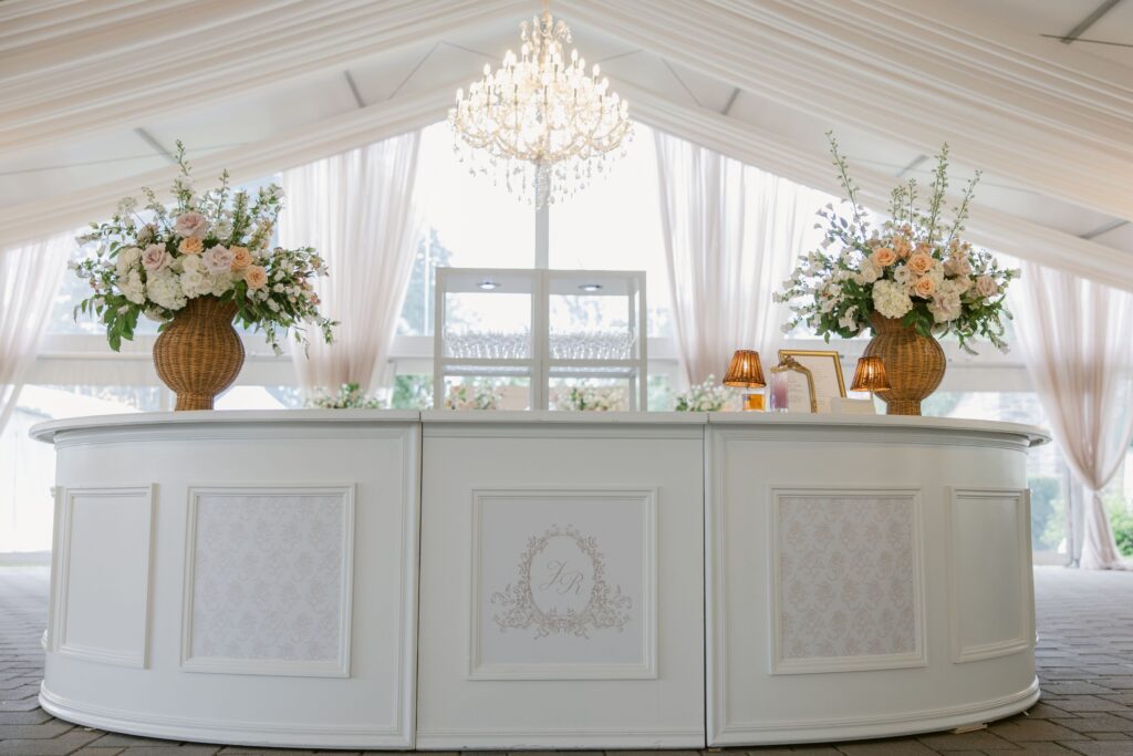luxury wedding round white bar with florals, a chandelier and draping