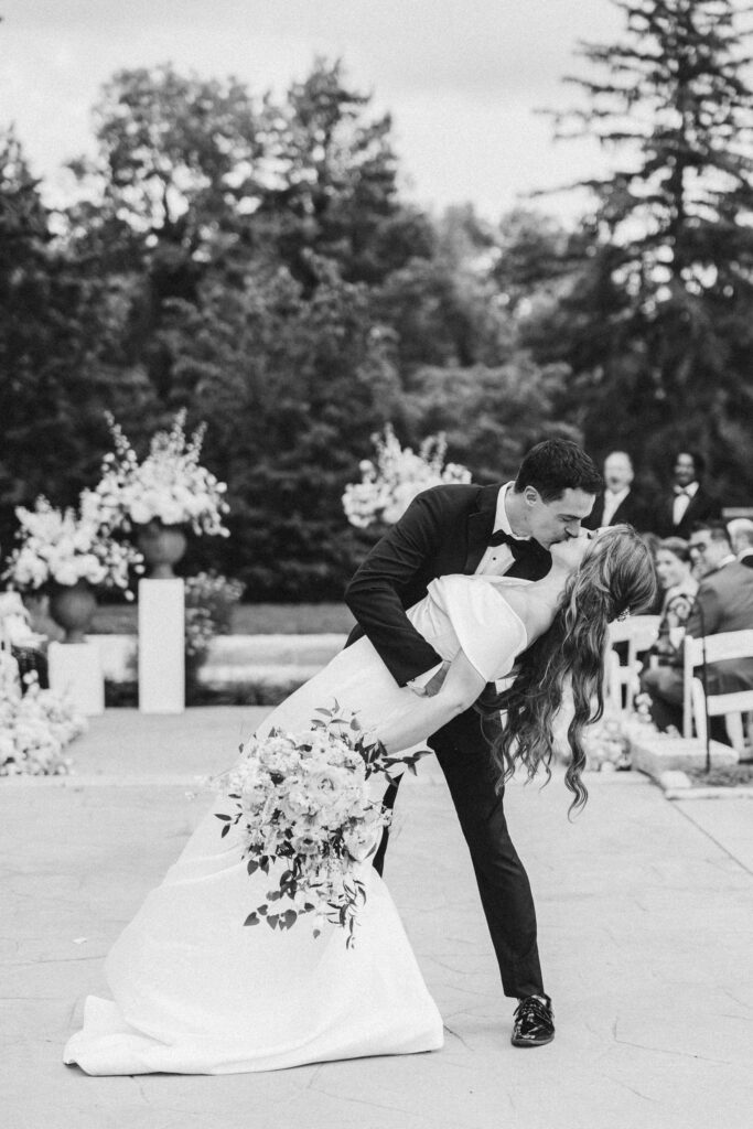 newly married couple kisses at the end of the aisle